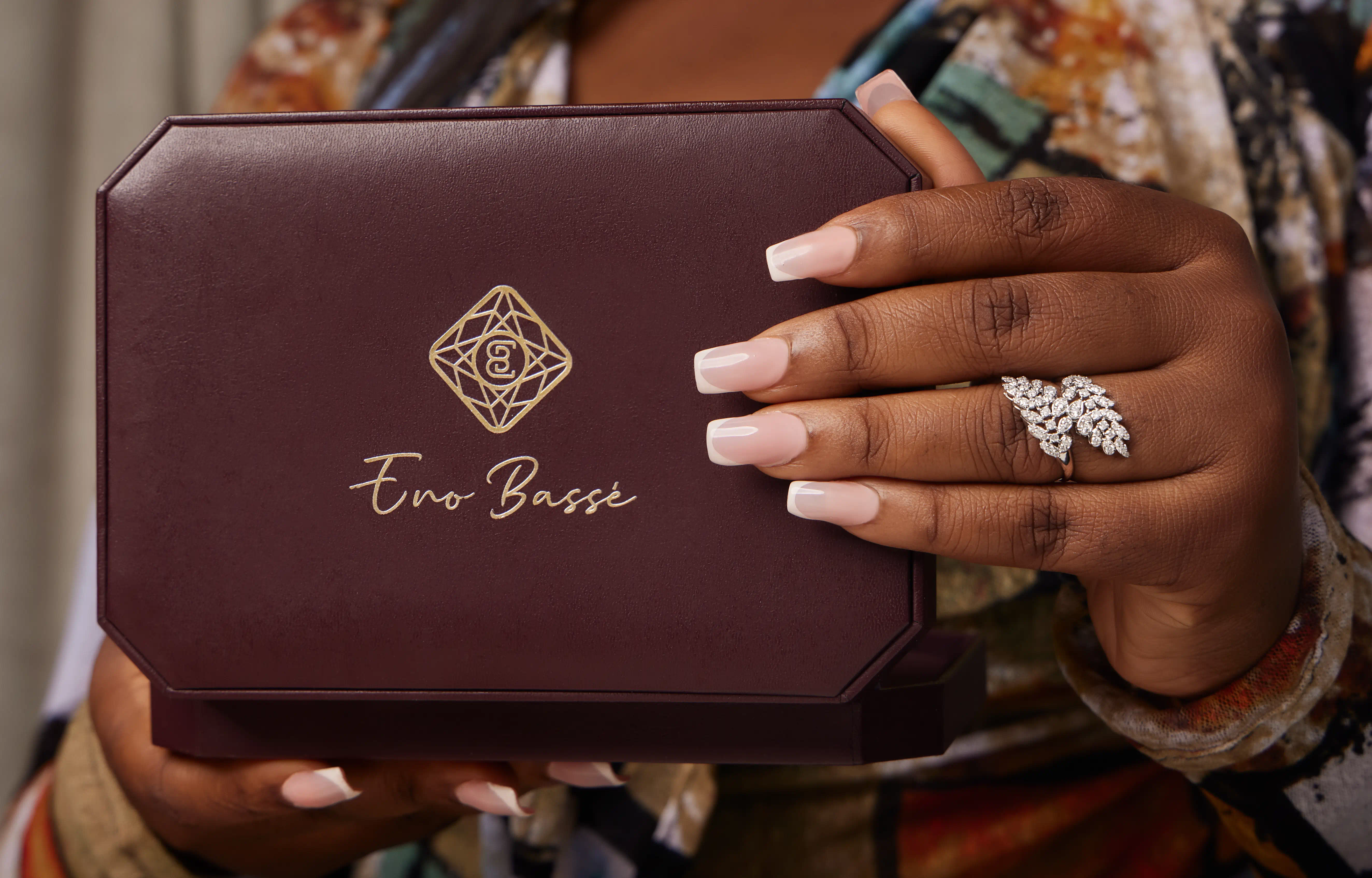Hand with leaf-styled white gold diamond ring holding an Eno Basse jewelry box